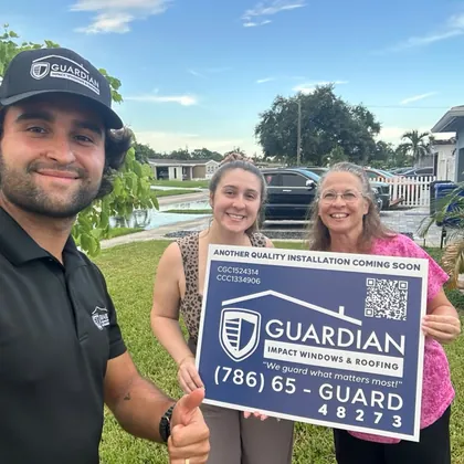 A Guardian project manager with homeowners and a Guardian yard sign
